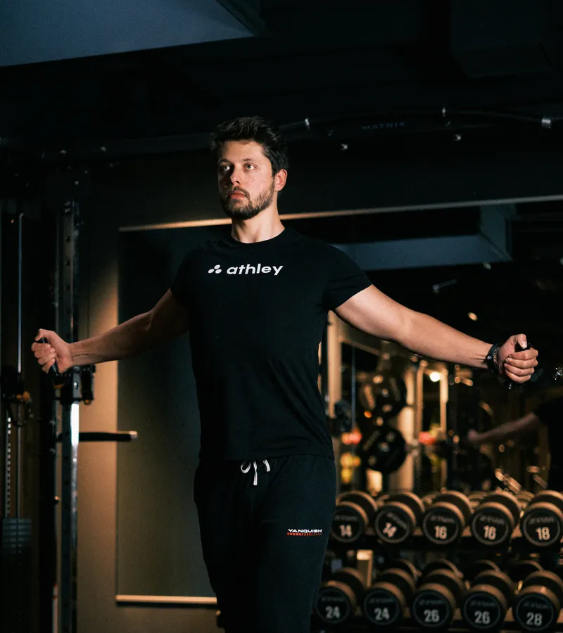 Coach in Athley-shirt traint met weerstandskabels in de gym