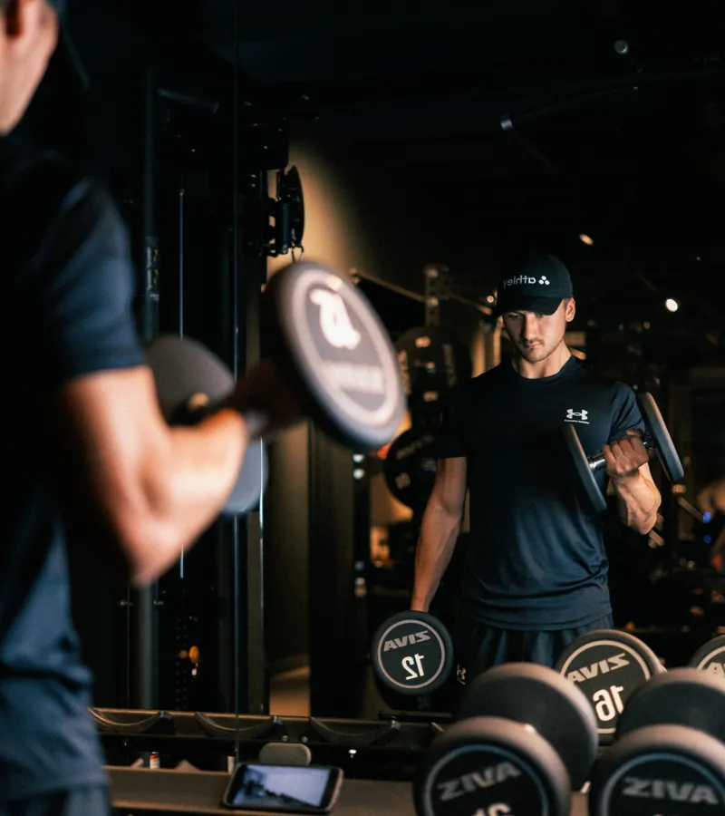 Sporter traint met dumbbells in een donkere gym