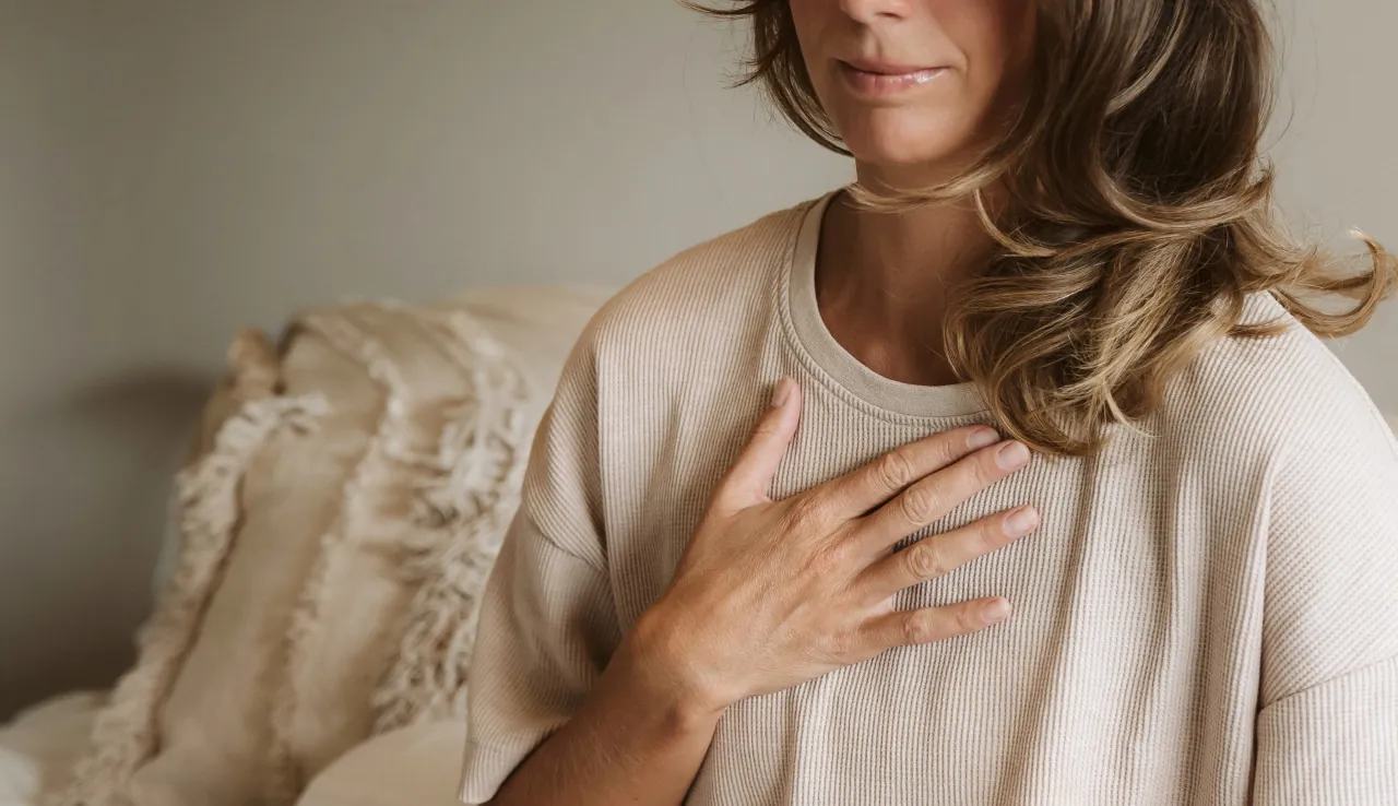 Vrouw zit rustig met haar hand op haar hart
