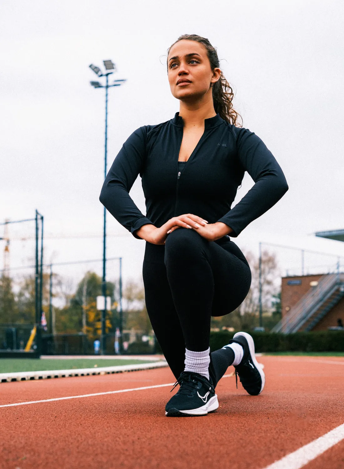 Vrouw doet een stretchoefening op een atletiekbaan